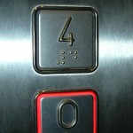 Braille illetve dombornyomott betűk alkalmazása lift gombon.