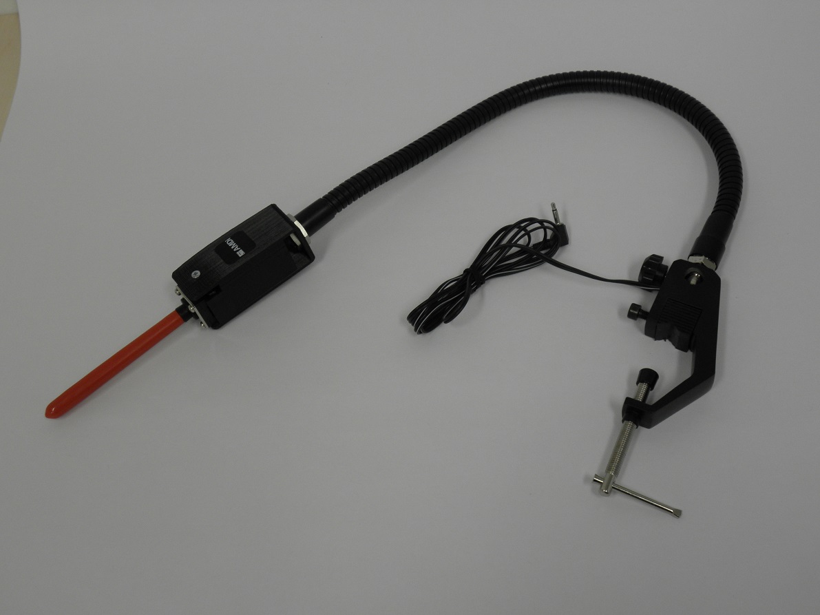 Hosszú fekete flexibilis fém szár a végén elhelyezett piros piros kapcsolószár, a másik végén a rögzítését segítő konzol és az eszközhöz tartozó kábel látható aképen.