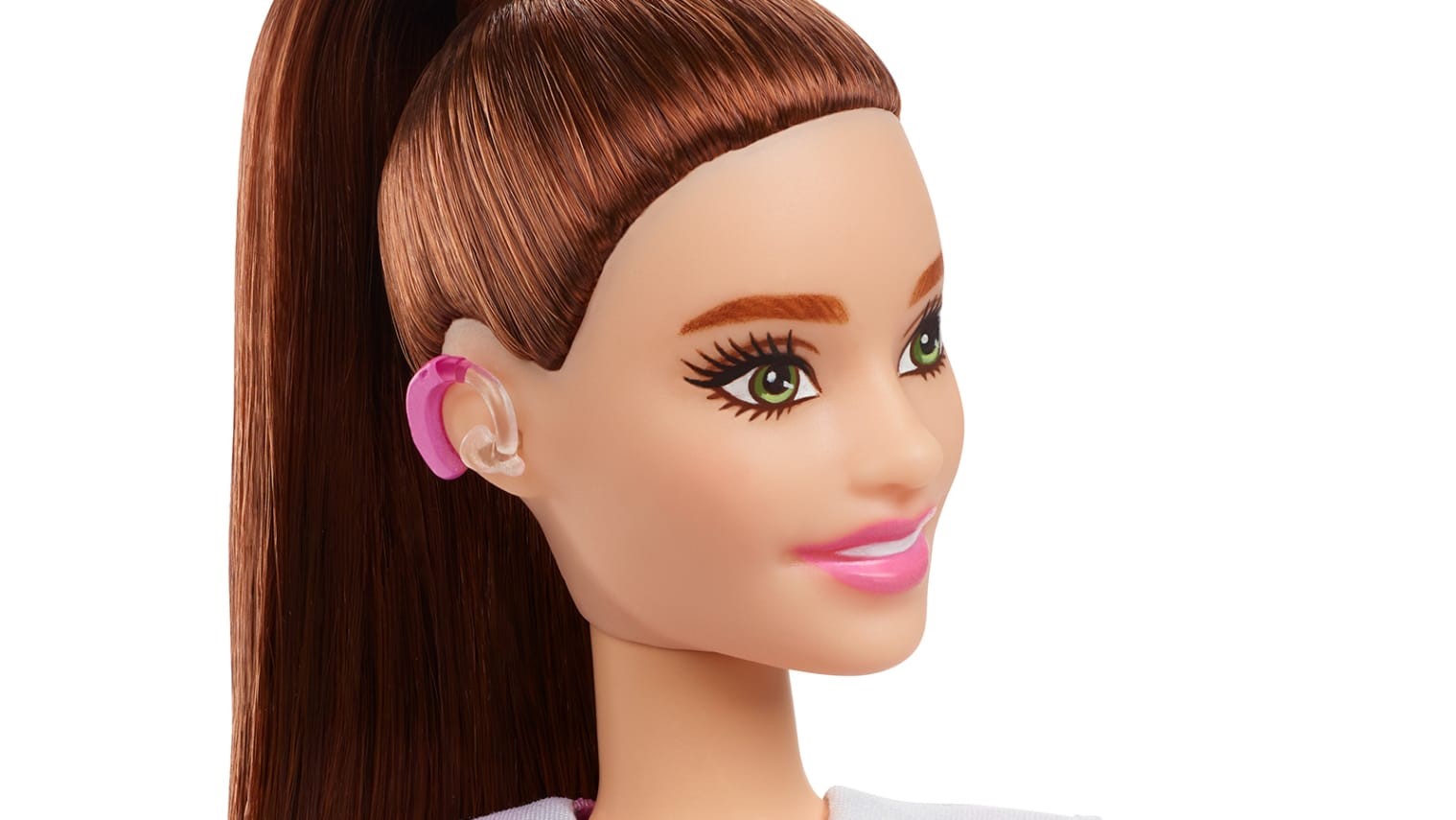 A képen egy barna hajú Barbiea baba feje látható oldalról. A füle mögött rózsaszín hallókészülék.